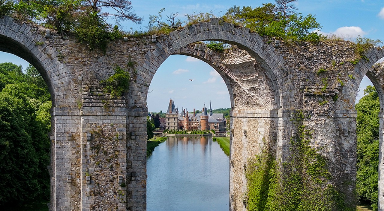 Le château de Maintenon aperçu à travers une arche de l'aqueduc, au-dessus du miroir d'eau de l'Eure.