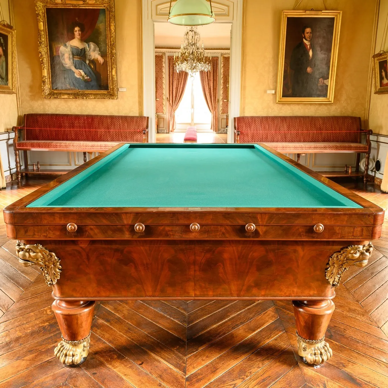 La pièce du billard du château de Maintenon : table de billard en acajou, portraits et banquettes.