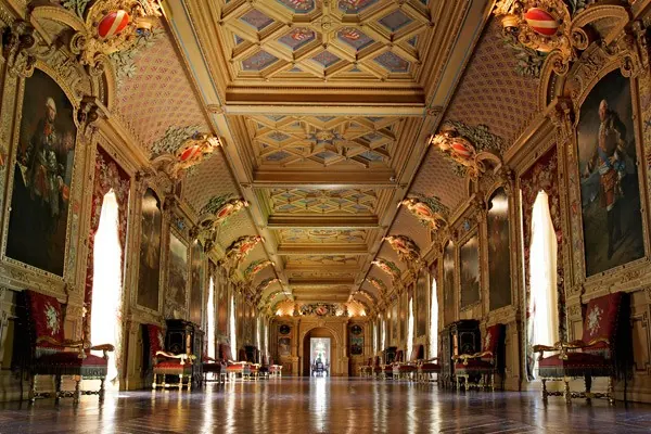 La grande galerie du château de Maintenon : plafond à caissons doré, grands portraits, fauteuils et banquettes de velours rouge.