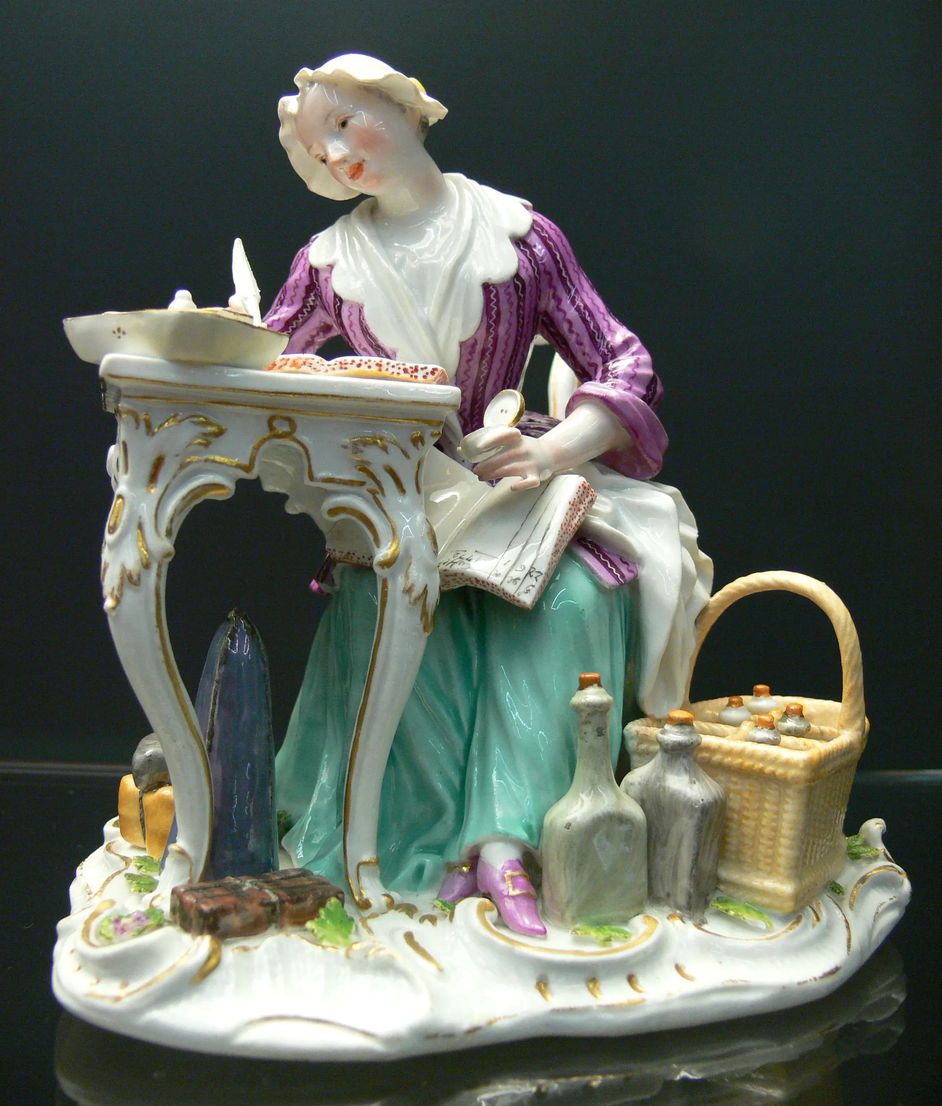 Figurine en porcelaine de Meissen : femme assise à une table de toilette, décor polychrome et or.