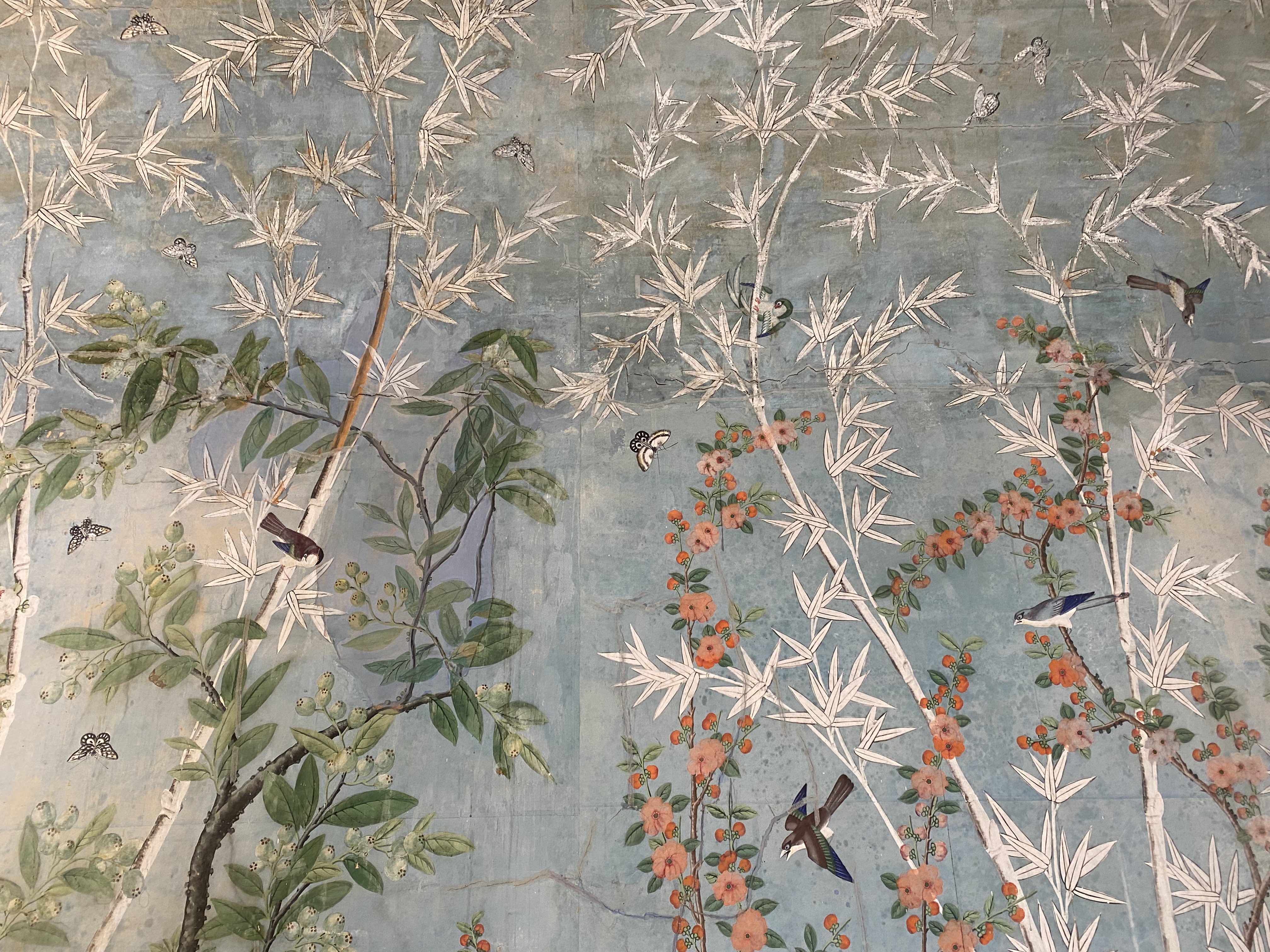 Papier peint chinois du XVIIIᵉ siècle : bambous, fleurs, oiseaux et papillons peints à la main sur fond bleu.