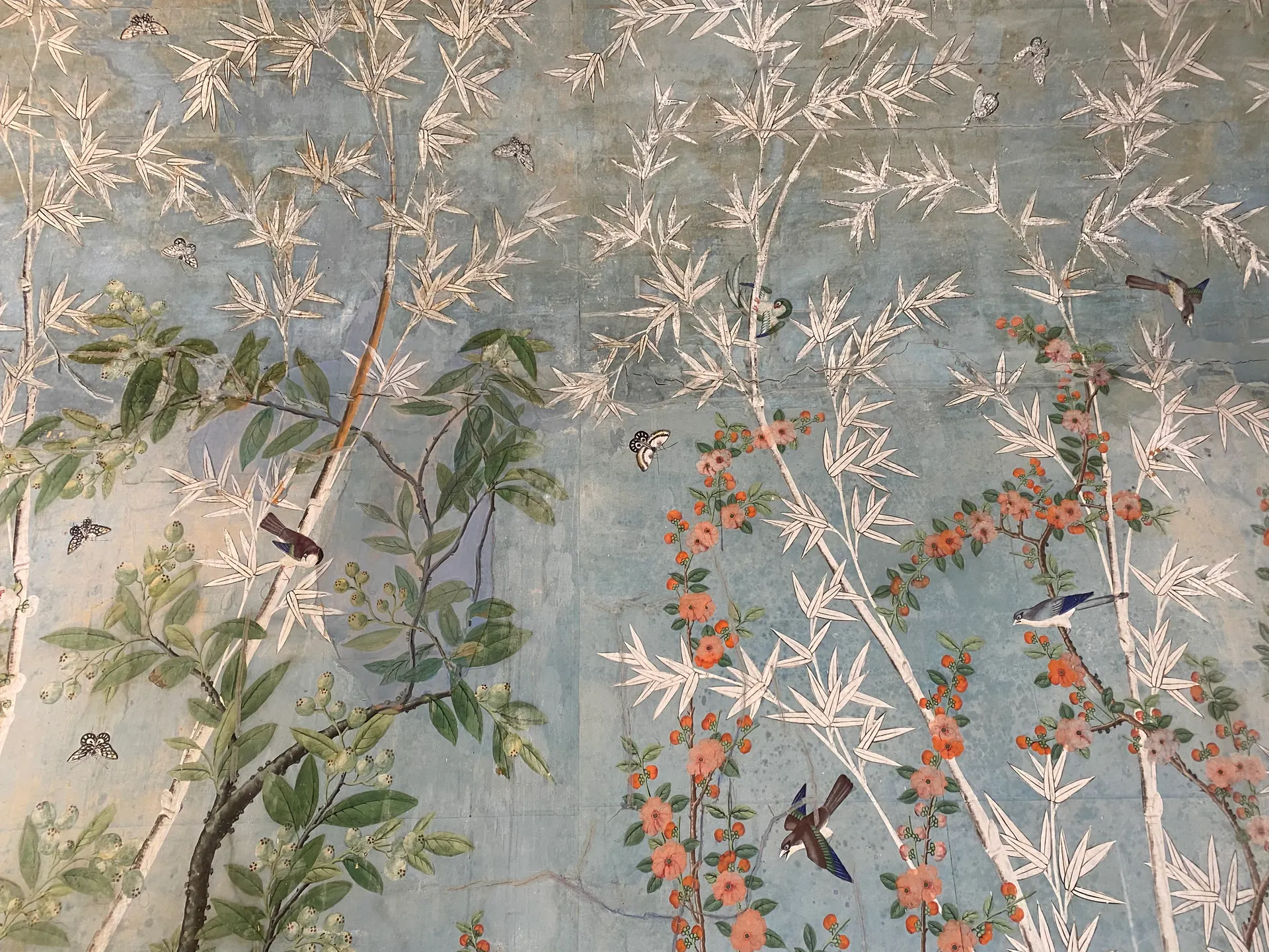 Papier peint chinois du XVIIIᵉ siècle : bambous, fleurs, oiseaux et papillons peints à la main sur fond bleu.