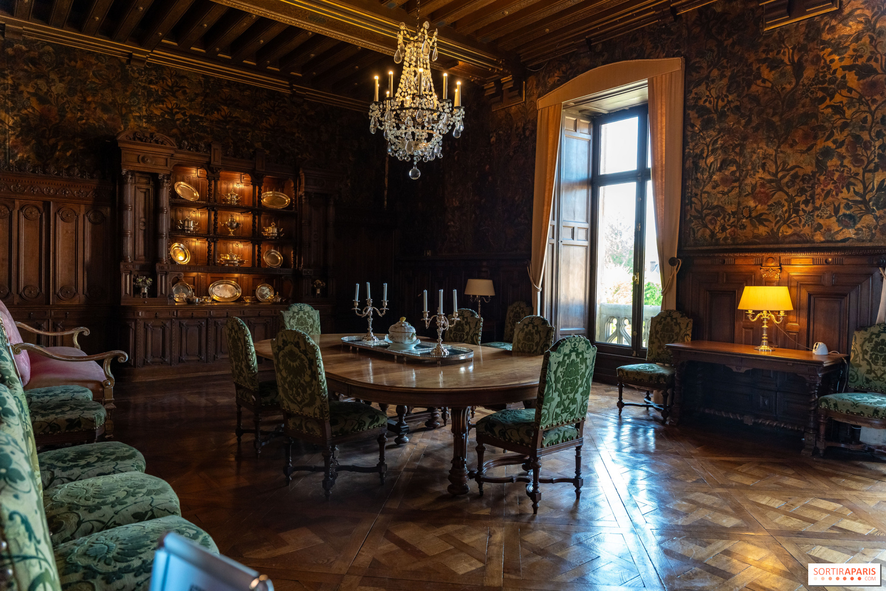 La salle à manger du château de Maintenon : murs de cuir, table dressée, vaisselier sculpté et lustre de cristal.